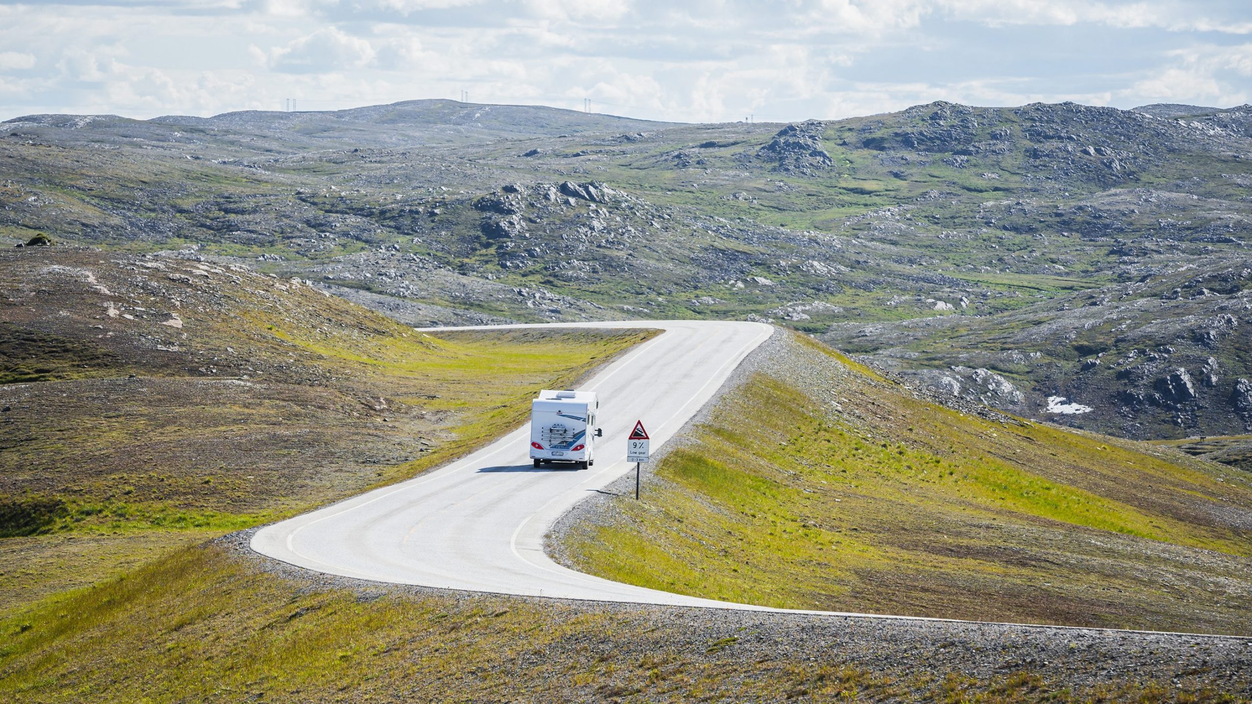 En bobil kjører på en vei i fjellandskap